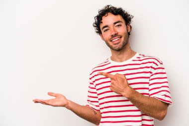 Beyaz arka planda izole edilmiş genç beyaz bir adam, palmiye üzerinde bir fotokopi alanı tutarken heyecanlı..