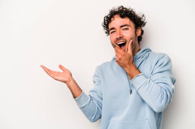 Beyaz arka planda izole edilmiş genç beyaz bir adam bir avuç içinde fotokopi alanı tutuyor, el üstünde tutuyor. Şaşırmış ve mutlu..