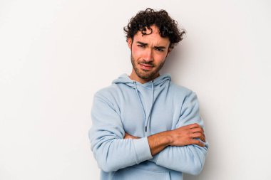 Beyaz arka planda izole edilmiş, hoşnutsuzca kaşlarını çatmış, kollarını kavuşturmuş genç beyaz bir adam..