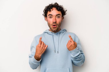 Beyaz arka planda izole edilmiş genç beyaz adam ağzı açık bir şekilde üst tarafı işaret ediyor..