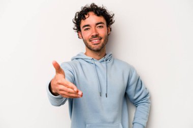 Beyaz arka planda izole edilmiş genç beyaz bir adam selamlama jesti olarak kameraya elini uzatıyor..
