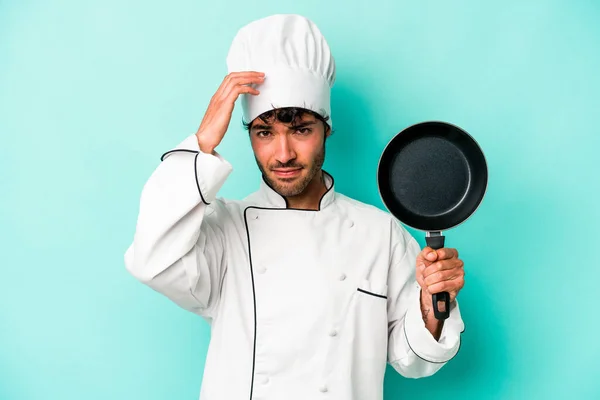 年轻的高加索厨师拿着一只被蓝色背景隔离的飞盘 被震惊了 她想起了重要的相遇 — 图库照片