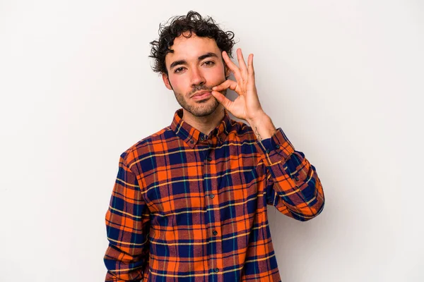 Beyaz arka planda izole edilmiş beyaz tenli genç bir adam parmakları dudaklarında bir sır saklıyor..