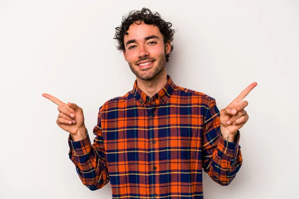 Beyaz arka planda izole edilmiş genç beyaz bir adam farklı kopya alanlarını gösteriyor, birini seçiyor, parmaklarıyla gösteriyor..