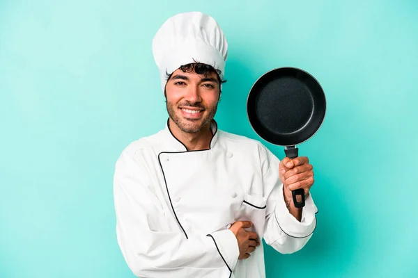 年轻的高加索厨师拿着被蓝色背景隔开的飞行锅 笑着玩乐 — 图库照片