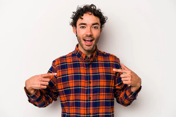 Beyaz arka planda izole edilmiş genç beyaz bir adam parmağını göstererek şaşırdı, geniş bir gülümsemeyle..