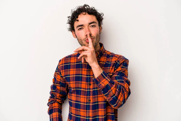 Beyaz arka planda izole edilmiş genç beyaz bir adam ya sır saklıyor ya da sessizlik istiyor..