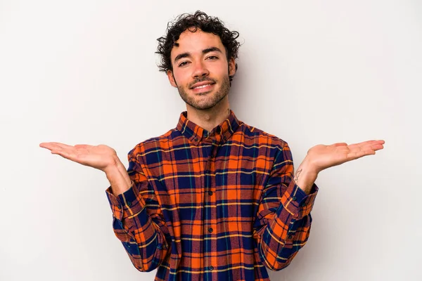 Beyaz arka planda izole genç beyaz adam kollarıyla ölçek yapar, mutlu ve kendinden emin hisseder..