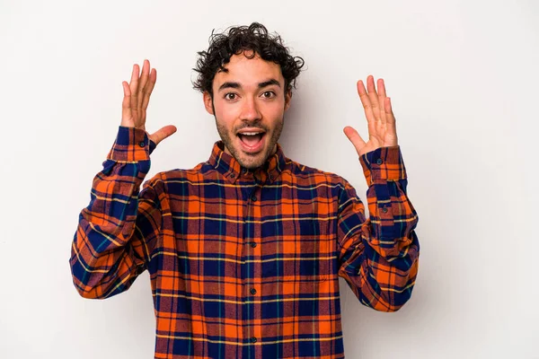 Beyaz arka planda izole olmuş genç beyaz bir adam zaferi veya başarıyı kutluyor, şaşırıyor ve şok oluyor..