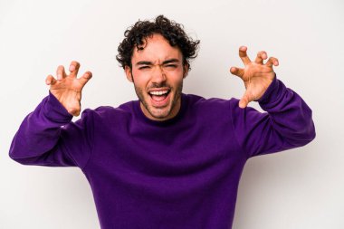 Beyaz arka planda izole edilmiş genç beyaz bir adam pençelerini kedi taklidi yaparken gösteriyor, agresif bir hareket..