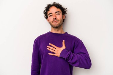 Beyaz arka planda izole edilmiş genç beyaz adam yemin ediyor, elini göğsüne koyuyor..