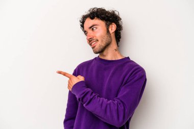 Beyaz arka planda izole edilmiş genç beyaz adam gülümseyen, neşeli ve keyifli bir tarafa bakıyor..