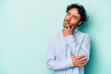 Beyaz arka planda izole edilmiş genç beyaz bir adam şüpheli ve şüpheci bir ifadeyle yana bakıyor..