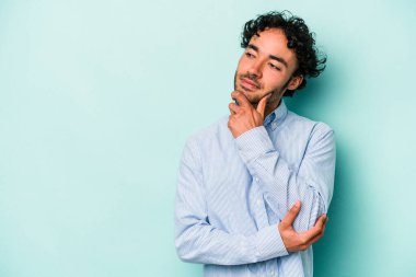 Beyaz arka planda izole edilmiş genç beyaz bir adam şüpheli ve şüpheci bir ifadeyle yana bakıyor..