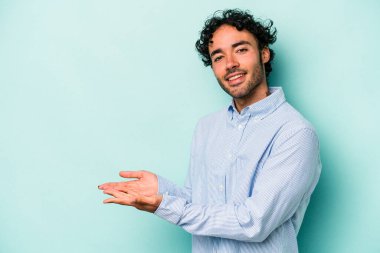 Beyaz arka planda izole edilmiş beyaz tenli genç bir adam palmiyesinde bir kopya alanı tutuyor..