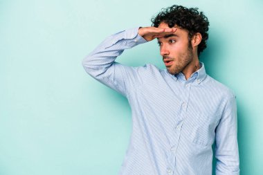 Beyaz arka planda izole edilmiş genç beyaz bir adam uzaklara bakıyor ve elini alnına koyuyor..