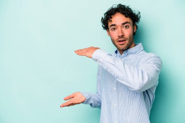 Beyaz arka planda izole edilmiş genç beyaz adam elleri arasında bir kopya alanı tutarken şok ve hayrete düştü..