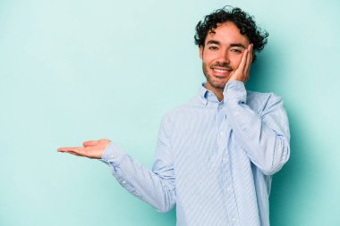 Beyaz arka planda izole edilmiş genç beyaz bir adam bir avuç içinde fotokopi alanı tutuyor, el üstünde tutuyor. Şaşırmış ve mutlu..