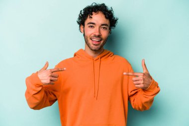 Beyaz arka planda izole edilmiş genç beyaz bir adam parmağını göstererek şaşırdı, geniş bir gülümsemeyle..