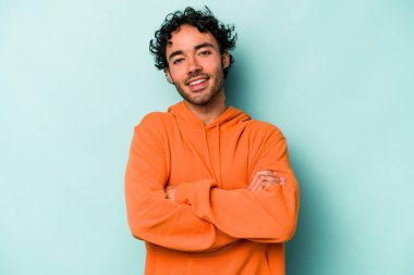 Beyaz arka planda kendini güvende hisseden, kararlılıkla kollarını kavuşturan beyaz tenli genç bir adam..