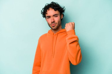 Beyaz arka planda izole edilmiş genç beyaz bir adam yumruğunu kameraya gösteriyor, agresif bir yüz ifadesi..