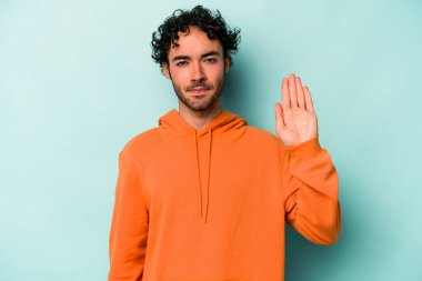 Beyaz arka planda izole edilmiş genç beyaz bir adam gülümseyerek beş numarayı parmaklarıyla gösteriyor..