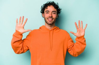 Beyaz arka planda izole edilmiş beyaz tenli genç adam on numarayı elleriyle gösteriyor..