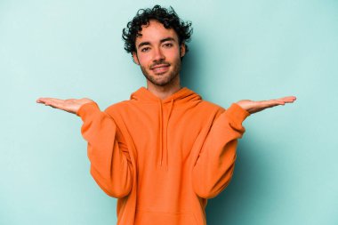 Beyaz arka planda izole genç beyaz adam kollarıyla ölçek yapar, mutlu ve kendinden emin hisseder..