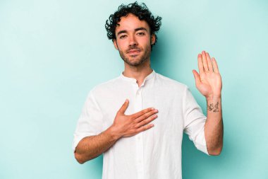 Beyaz arka planda izole edilmiş genç beyaz adam yemin ediyor, elini göğsüne koyuyor..