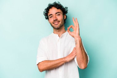 Beyaz arka planda izole edilmiş genç beyaz bir adam bir göz kırptı ve elleriyle iyi bir jest yaptı..