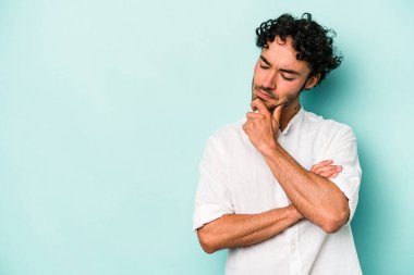 Beyaz arka planda izole edilmiş genç beyaz bir adam şüpheli ve şüpheci bir ifadeyle yana bakıyor..