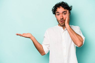 Beyaz arka planda izole edilmiş genç beyaz adam, avuç içi fotokopi alanını elinde tutmaktan etkilenmiş..