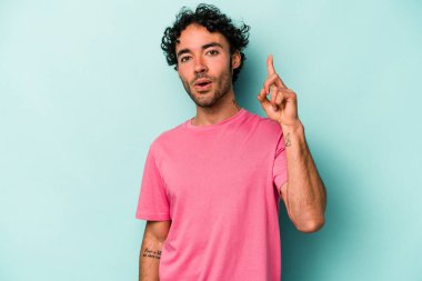 Beyaz arka planda izole edilmiş genç beyaz adam ağzı açık bir şekilde üst tarafı işaret ediyor..