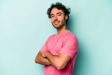 Beyaz arka planda kendini güvende hisseden, kararlılıkla kollarını kavuşturan beyaz tenli genç bir adam..