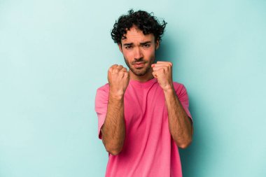 Beyaz arka planda izole edilmiş genç beyaz bir adam yumruğunu kameraya gösteriyor, agresif bir yüz ifadesi..