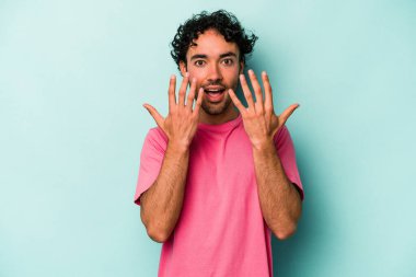 Beyaz arka planda izole edilmiş beyaz tenli genç adam on numarayı elleriyle gösteriyor..