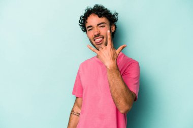 Beyaz arka planda izole edilmiş genç beyaz bir adam parmaklarıyla kaya hareketi gösteriyor.