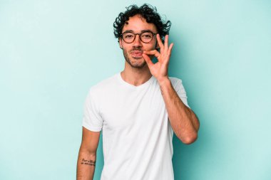 Beyaz arka planda izole edilmiş beyaz tenli genç bir adam parmakları dudaklarında bir sır saklıyor..