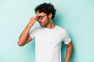 Beyaz arka planda izole olmuş genç beyaz bir adam başı ağrıyor, yüzüne dokunuyor..