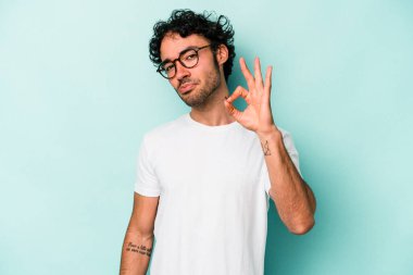 Beyaz arka planda izole edilmiş genç beyaz bir adam bir göz kırptı ve elleriyle iyi bir jest yaptı..