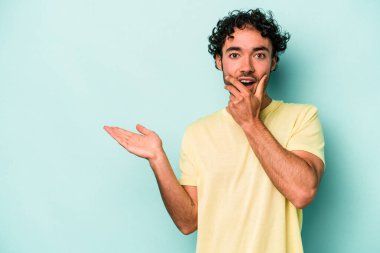 Beyaz arka planda izole edilmiş genç beyaz bir adam bir avuç içinde fotokopi alanı tutuyor, el üstünde tutuyor. Şaşırmış ve mutlu..