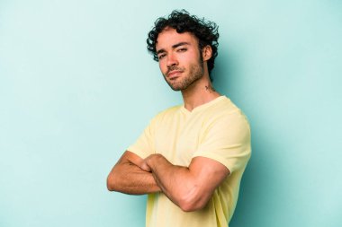 Beyaz arka planda izole edilmiş, hoşnutsuzca kaşlarını çatmış, kollarını kavuşturmuş genç beyaz bir adam..