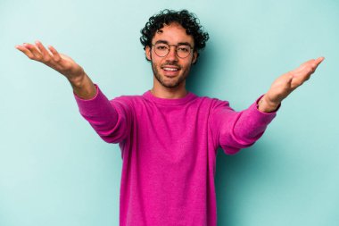 Beyaz arka planda izole olmuş genç beyaz bir adam zaferi veya başarıyı kutluyor, şaşırıyor ve şok oluyor..