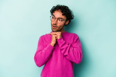 Beyaz arka planda izole edilmiş genç beyaz bir adam şans için dua ediyor, şaşırmış ve ağzını açıp önüne bakıyor..