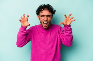 Beyaz arka planda izole edilmiş genç beyaz bir adam pençelerini kedi taklidi yaparken gösteriyor, agresif bir hareket..