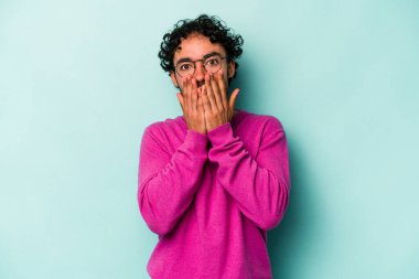 Beyaz arka planda izole edilmiş genç beyaz adam şok olmuş, ağzı ellerle kaplanmış, yeni bir şey keşfetmeye hevesli..