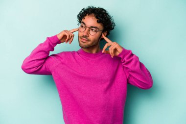 Beyaz arka planda izole edilmiş genç beyaz bir adam parmaklarıyla kulaklarını kapatıyor, gürültülü bir ortam yüzünden stresli ve çaresiz..