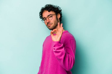 Beyaz arka planda izole edilmiş genç beyaz bir adam bir göz kırptı ve elleriyle iyi bir jest yaptı..