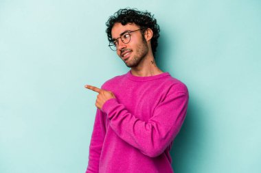 Beyaz arka planda izole edilmiş genç beyaz adam gülümseyen, neşeli ve keyifli bir tarafa bakıyor..