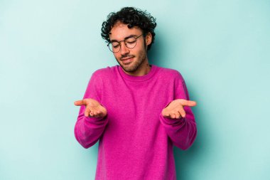 Beyaz arka planda izole edilmiş genç beyaz bir adam elinde avuç içi bir şeyle kameraya sunuyor..